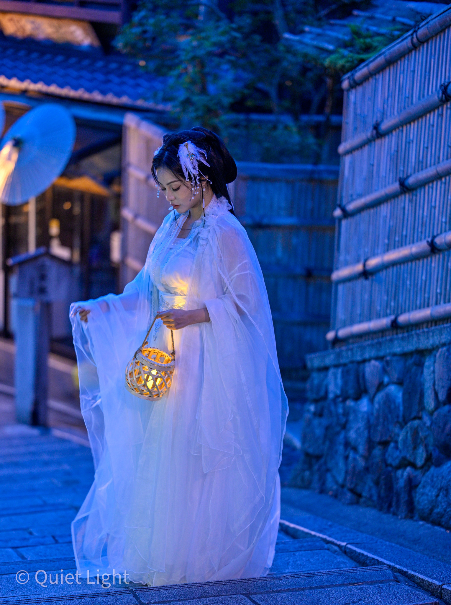 Soft expression, model looking down at lantern.